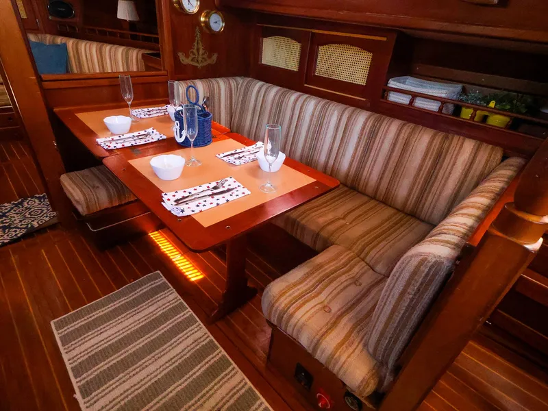 Slide: The Image of Cozy dining area in a 1987 Gozzard 36 sailboat with striped seating and wooden table. - 35