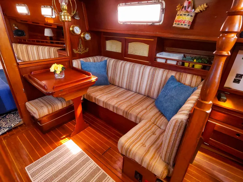 Slide: The Image of Cozy interior of 1987 Gozzard 36 sailboat with striped seating and wooden accents. - 38