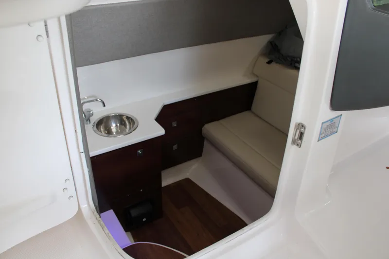 Slide: The Image of 2021 Chaparral 280 OSX cabin interior with sink, seating, and storage. - 12