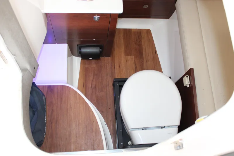 Slide: The Image of 2021 Chaparral 280 OSX boat interior with wooden flooring and compact toilet. - 13