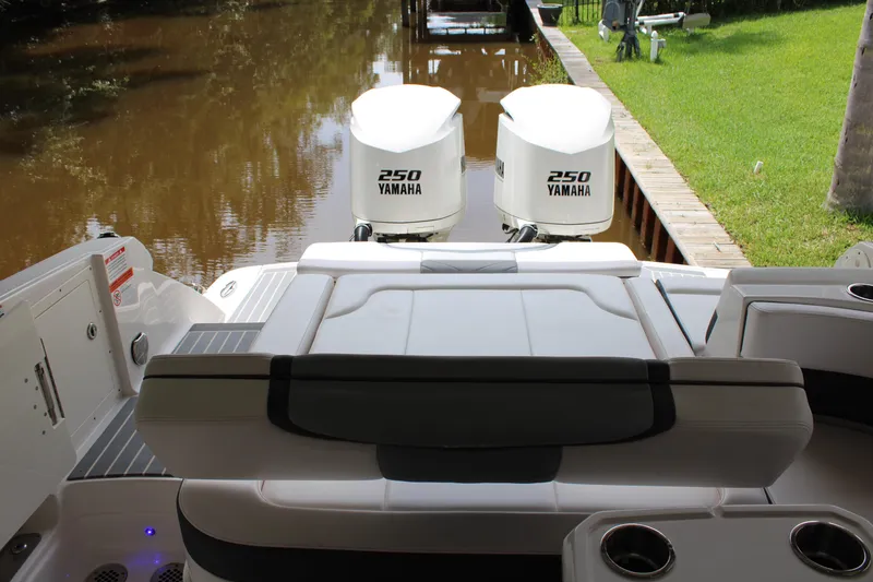 Slide: The Image of 2021 Chaparral 280 OSX boat with twin Yamaha 250 engines docked by a grassy area. - 15