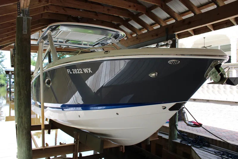Slide: The Image of 2021 Chaparral 280 OSX boat docked under a wooden shelter. - 2