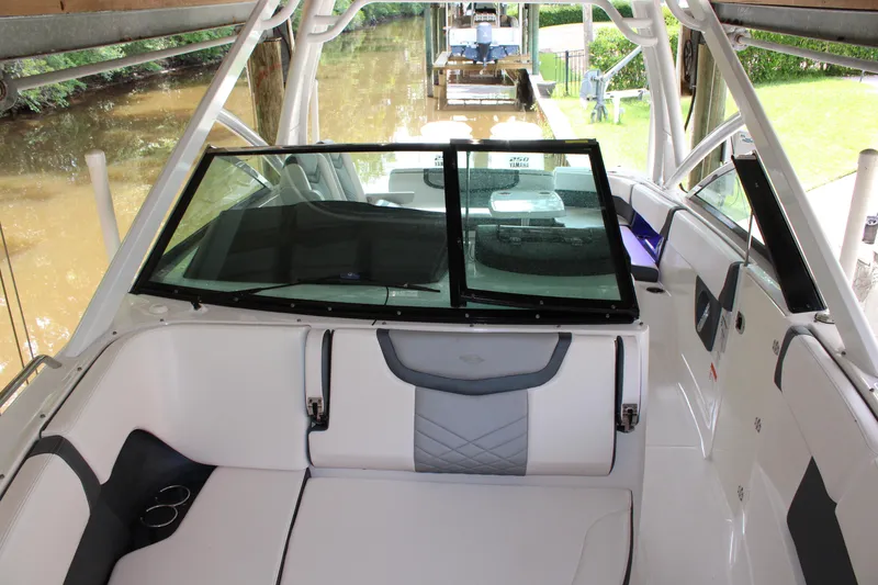 Slide: The Image of 2021 Chaparral 280 OSX boat interior with seating and windshield, docked by a river. - 25