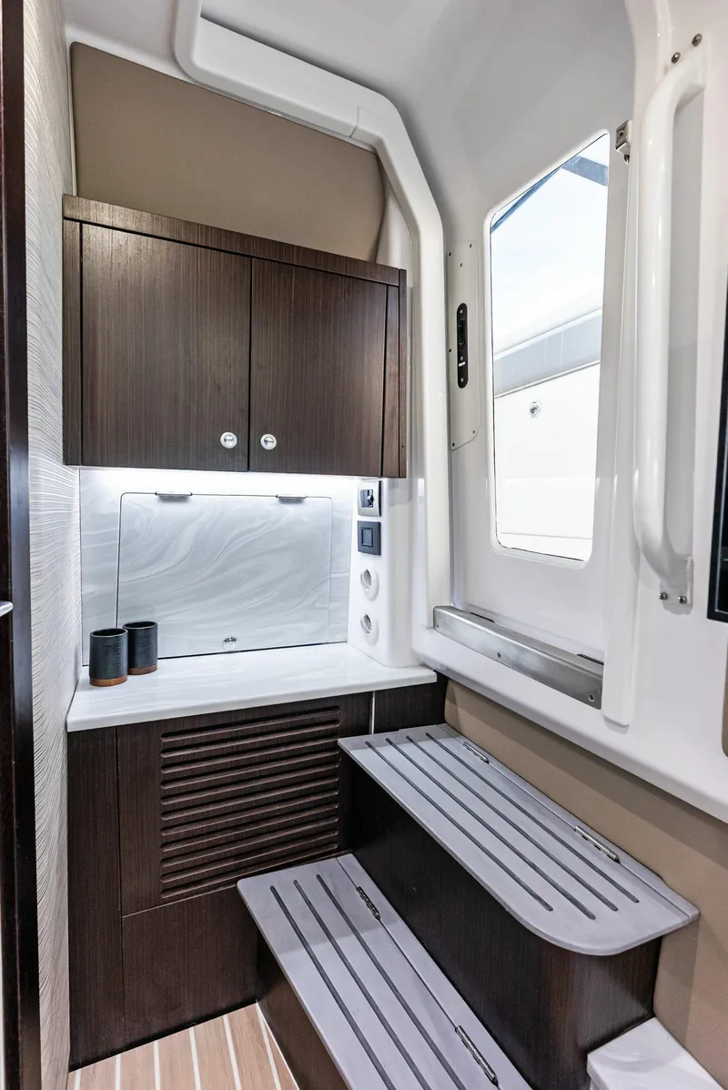 Slide: The Image of 2026 Everglades 367 CX boat interior with seating and storage at a marina. - 12