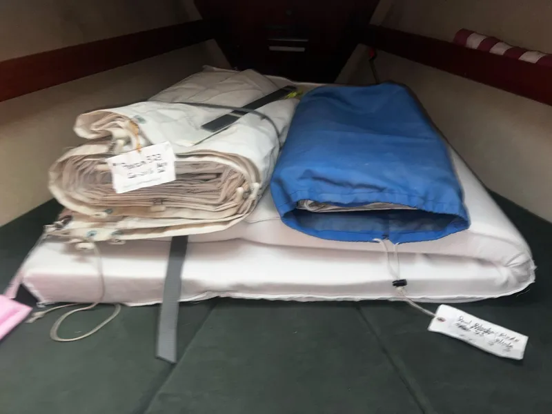 Slide: The Image of Folded sails inside a 1980 Pearson 32 sailboat cabin, labeled and organized. - 10