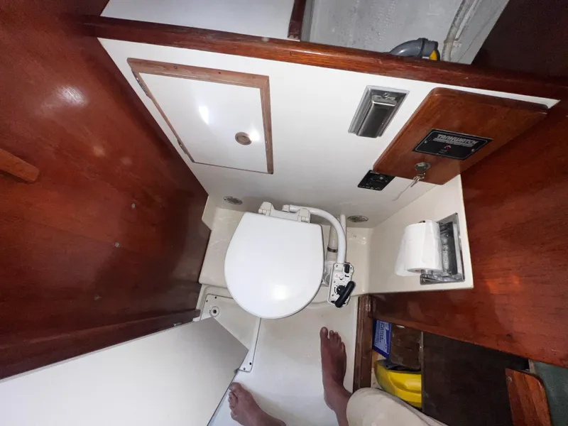 Slide: The Image of Compact marine bathroom in a 1980 Pearson 32 sailboat, featuring a toilet and wooden cabinetry. - 11