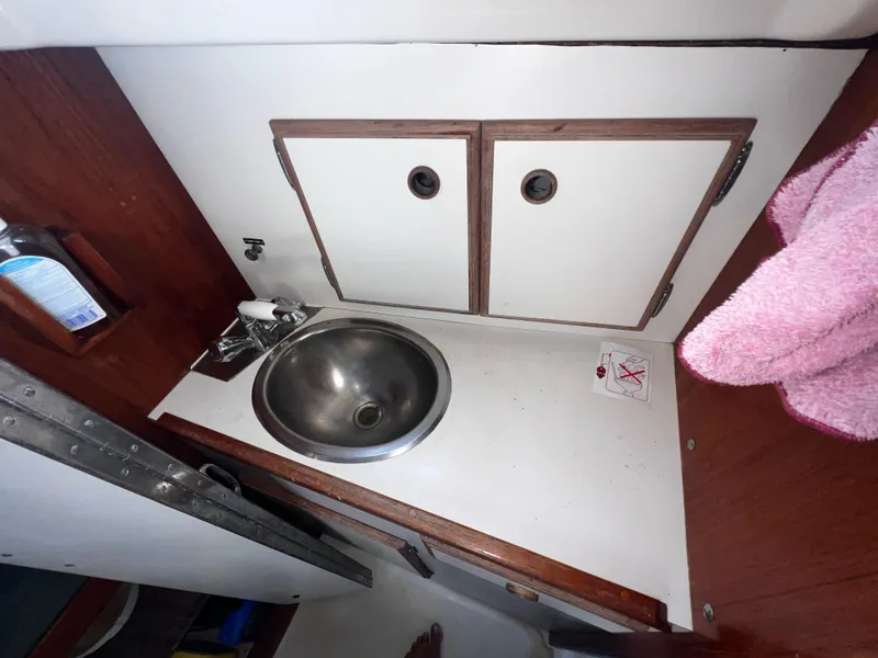 Slide: The Image of Compact bathroom sink area in a 1980 Pearson 32 sailboat, featuring wooden cabinetry. - 15