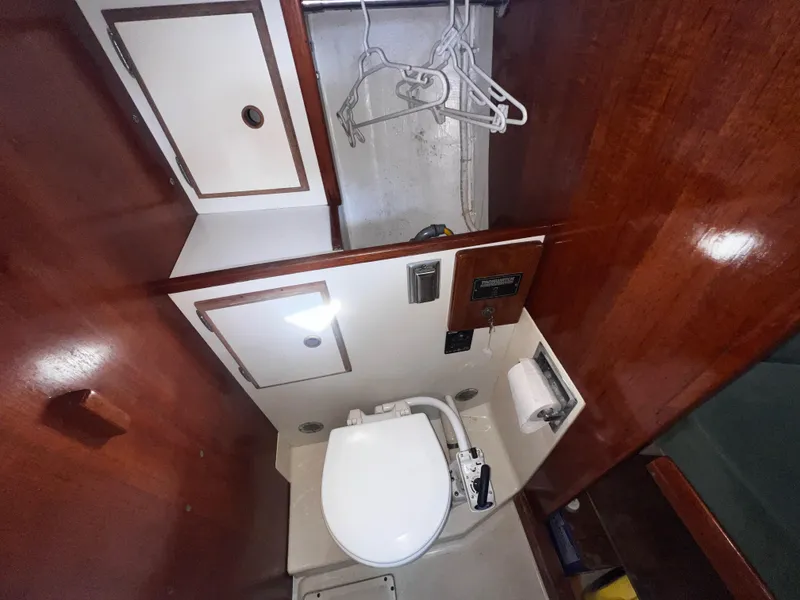 Slide: The Image of 1980 Pearson 32 sailboat bathroom with wooden cabinets and marine toilet. - 16