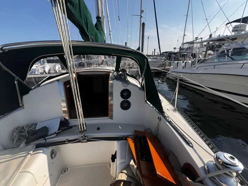 Slide: The Image of 1980 Pearson 32 sailboat cockpit view in marina, surrounded by other boats. - 22