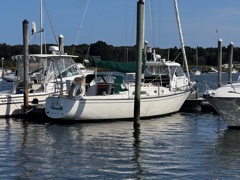 Slide: The Image of 1980 Pearson 32 sailboat docked at marina, surrounded by other boats, calm water. - 4