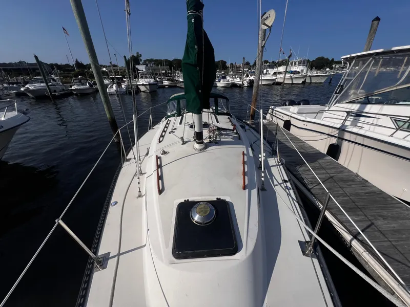 Slide: The Image of 1980 Pearson 32 sailboat docked in a marina, surrounded by other boats. - 7