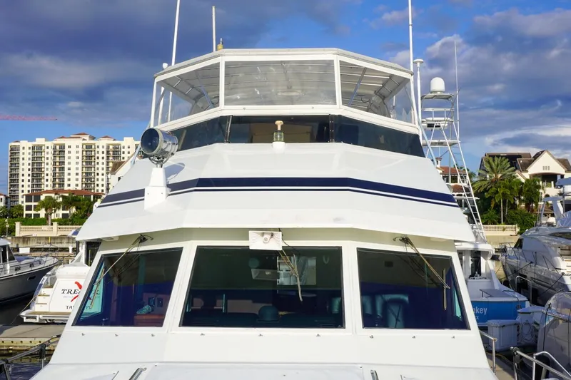 Slide: The Image of 1990 Hatteras 62 Cockpit Motor Yacht docked at marina, with buildings in background. - 13