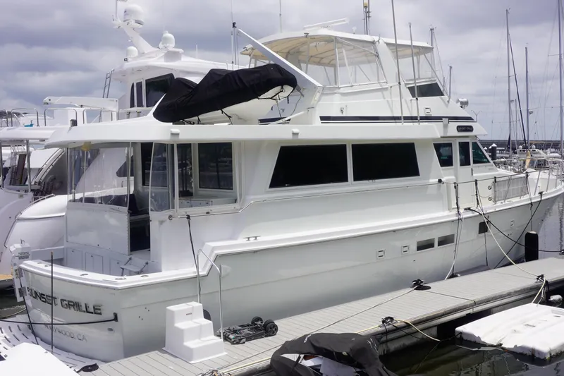 Slide: The Image of 1990 Hatteras 62 Cockpit Motor Yacht docked at marina under cloudy skies. - 2