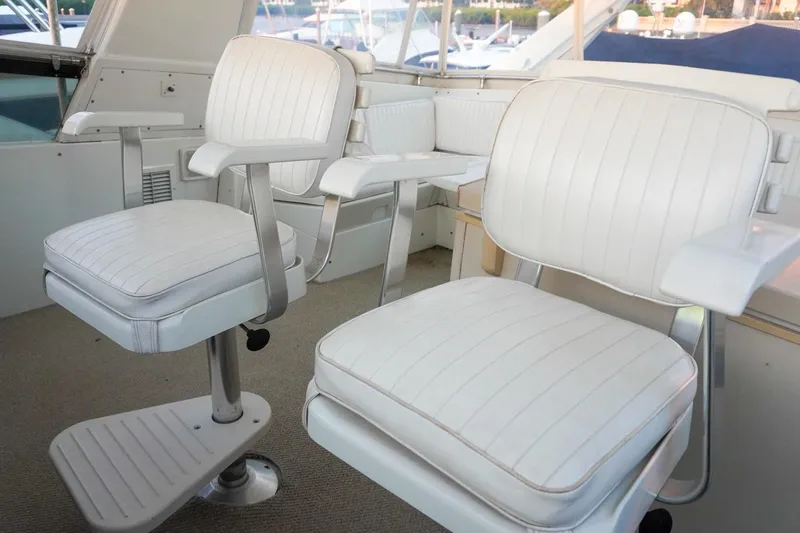 Slide: The Image of White seating area on 1990 Hatteras 62 Cockpit Motor Yacht, featuring plush chairs and elegant design. - 23