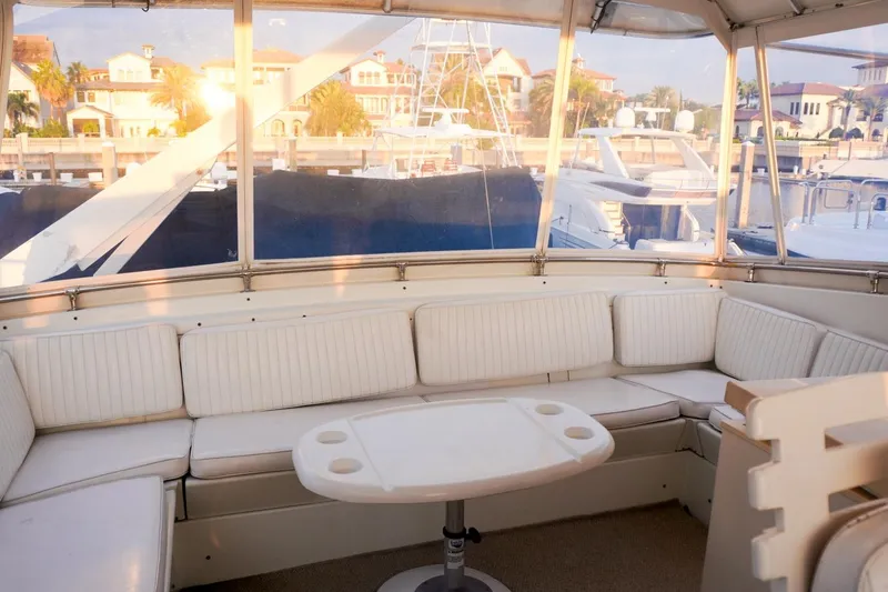 Slide: The Image of Luxurious 1990 Hatteras 62 Cockpit Motor Yacht interior with white seating and marina view. - 26