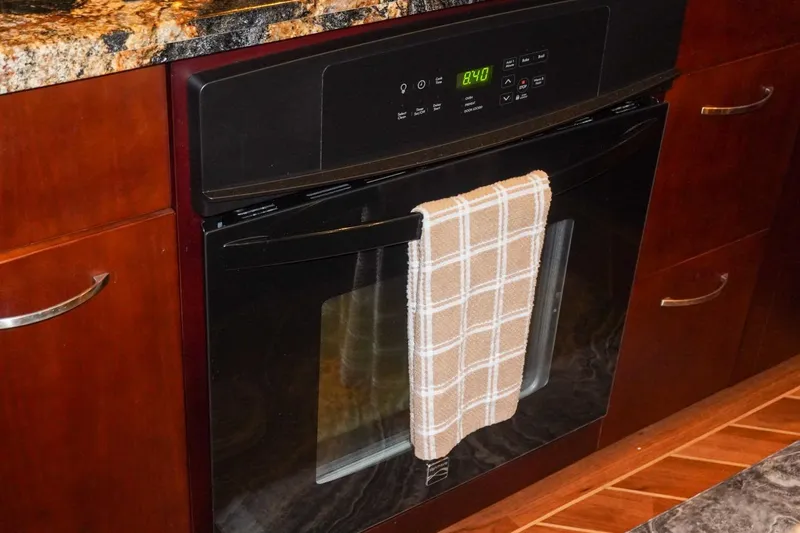 Slide: The Image of Built-in oven with digital display and plaid towel, inside a Hatteras 62 Cockpit Motor Yacht kitchen. - 39