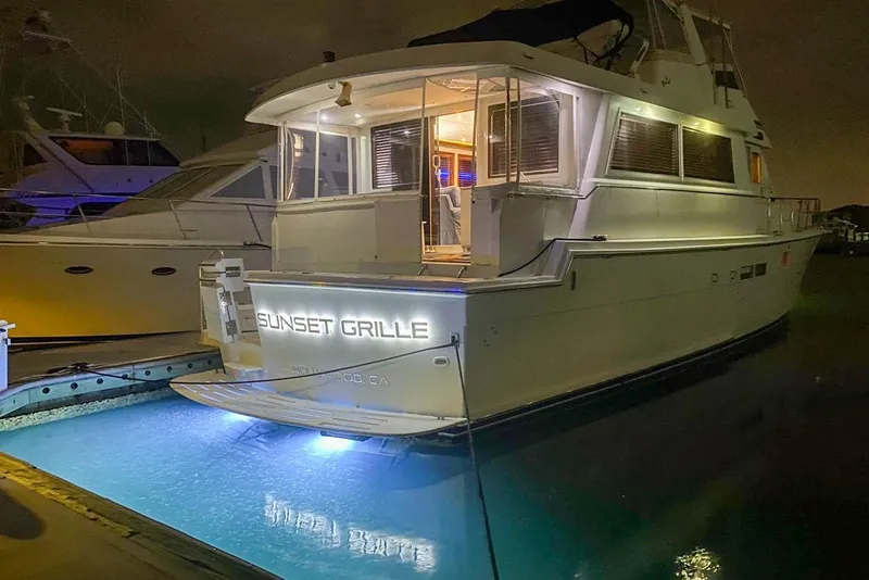 Slide: The Image of 1990 Hatteras 62 Cockpit Motor Yacht docked at night with illuminated nameplate. - 4