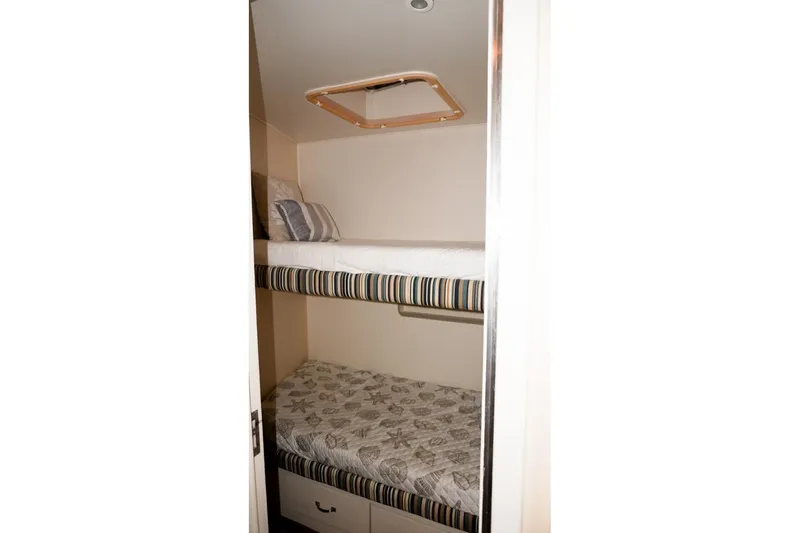 Slide: The Image of Bunk beds in 1990 Hatteras 62 Cockpit Motor Yacht cabin, featuring striped and patterned bedding. - 46