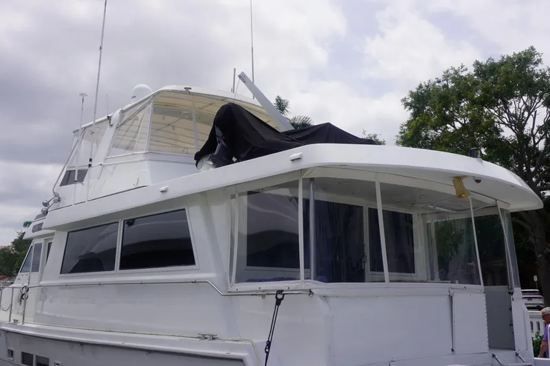 Slide: The Image of 1990 Hatteras 62 Cockpit Motor Yacht with enclosed deck, docked under cloudy skies. - 6