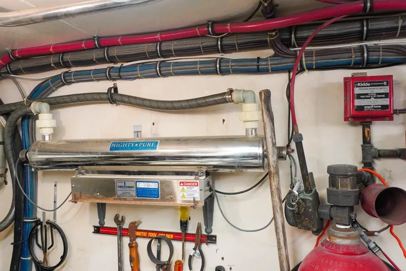 Slide: The Image of Engine room of 1990 Hatteras 62 Cockpit Motor Yacht with water purifier and tools. - 64