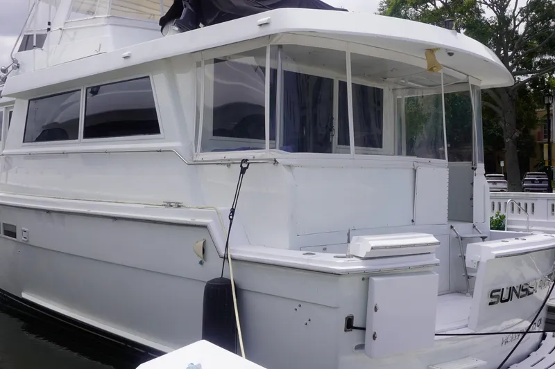 Slide: The Image of 1990 Hatteras 62 Cockpit Motor Yacht docked, featuring spacious deck and sleek design. - 7