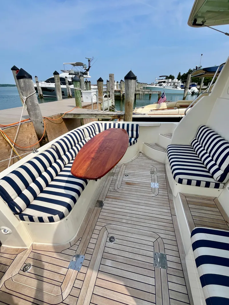 Slide: The Image of 2010 Sabre 40 Sedan yacht with striped seating and wooden table at a marina. - 11