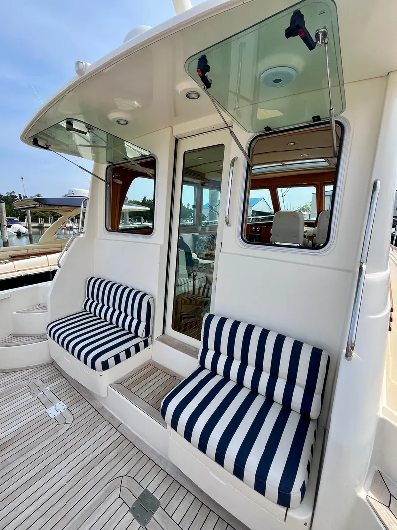 Slide: The Image of 2010 Sabre 40 Sedan yacht with striped seating and glass doors, docked at a marina. - 12