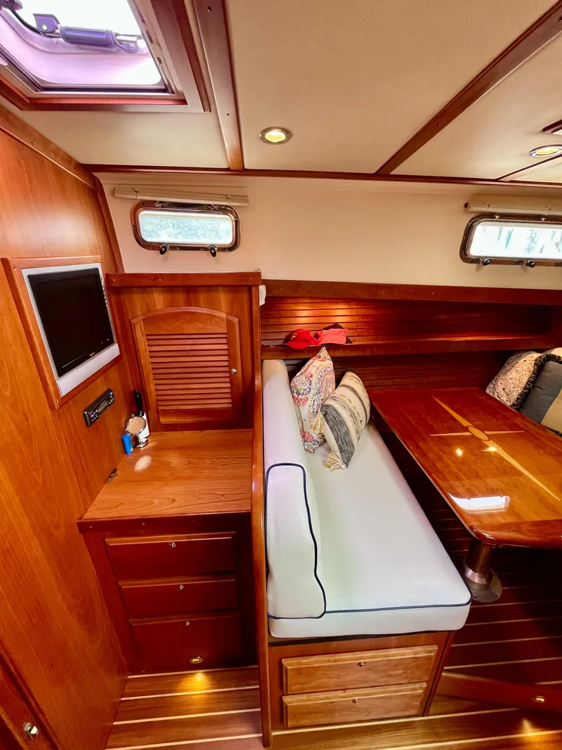 Slide: The Image of 2010 Sabre 40 Sedan interior with wooden cabinetry, cushioned seating, and a mounted TV. - 28