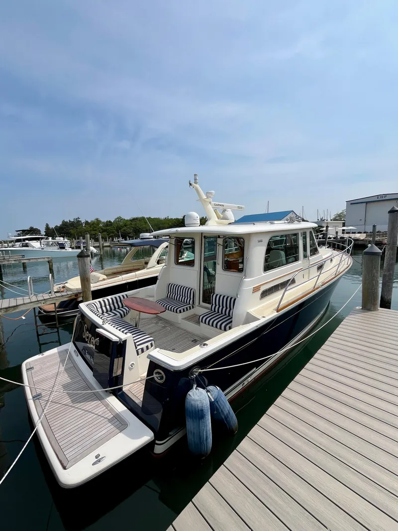 Slide: The Image of 2010 Sabre 40 Sedan yacht docked at marina with striped seating and clear skies. - 3