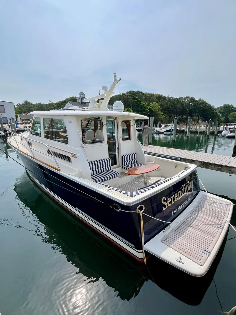 Slide: The Image of 2010 Sabre 40 Sedan yacht docked, featuring elegant design and spacious deck seating. - 6