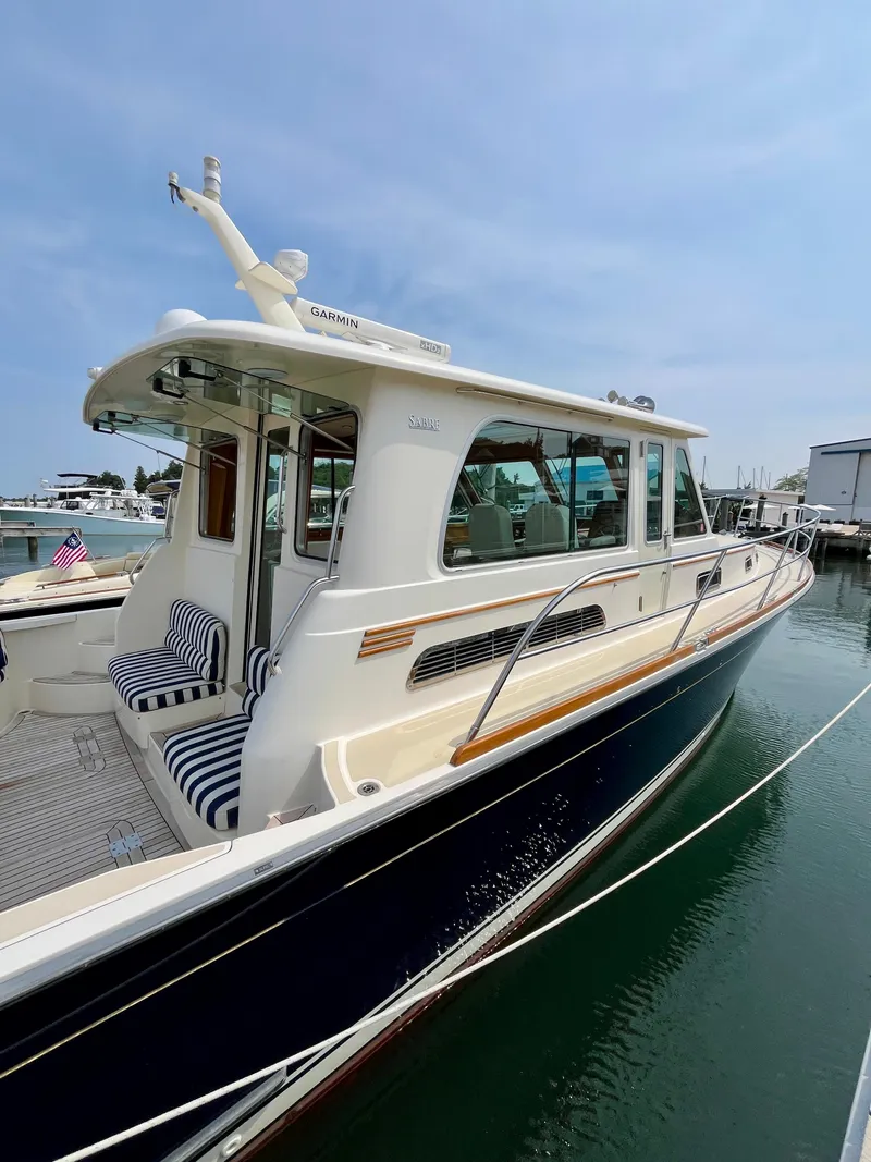 Slide: The Image of 2010 Sabre 40 Sedan yacht docked, featuring sleek design and striped seating. - 8