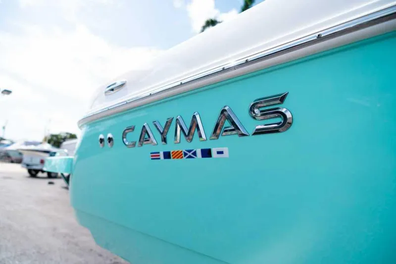 Slide: The Image of 2024 Caymas 281 HB boat, turquoise hull with chrome logo and nautical flags. - 4