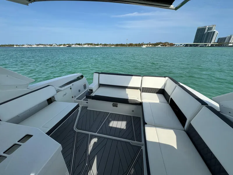 Slide: The Image of 2018 Monterey 378 Super Express boat interior with luxurious seating, overlooking serene waters and distant buildings. - 9