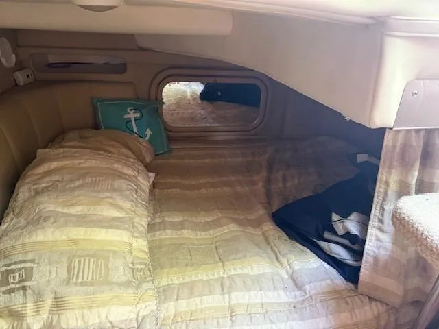 Slide: The Image of 2003 Rinker Fiesta Vee 342 cabin interior with bed and nautical-themed pillow. - 14
