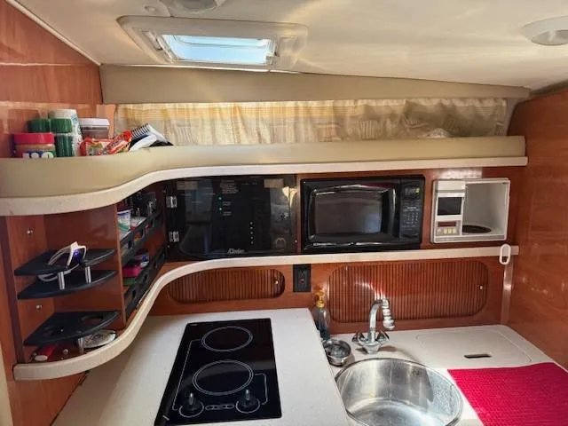 Slide: The Image of 2003 Rinker Fiesta Vee 342 kitchen area with stove, microwave, and sink. - 16