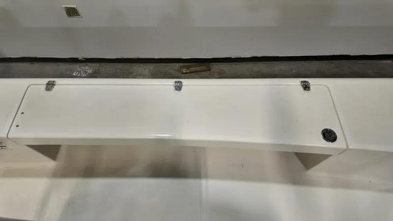 Slide: The Image of 2025 Spyder FX19 Vapor boat storage compartment with white lid and metal hinges. - 22