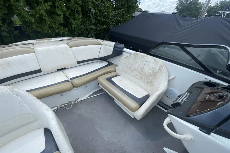 Slide: The Image of 2005 Sea-Doo Utopia 185 boat interior with beige and white seating, near greenery. - 13