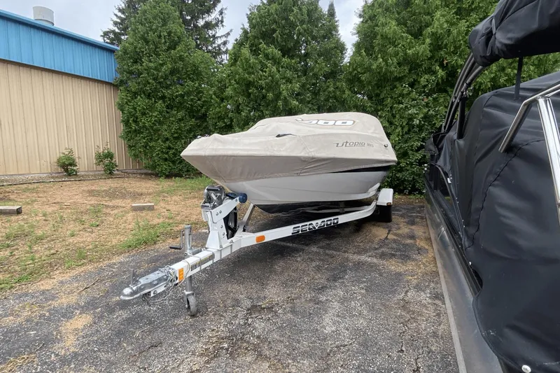 Slide: The Image of 2005 Sea-Doo Utopia 185 boat covered on trailer, parked outdoors. - 22