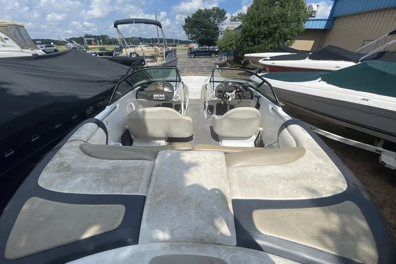 Slide: The Image of 2005 Sea-Doo Utopia 185 boat interior with seating and steering wheel, parked outdoors. - 3