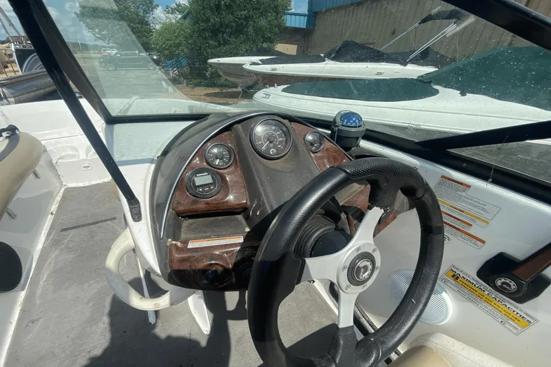 Slide: The Image of 2005 Sea-Doo Utopia 185 dashboard with steering wheel and gauges, docked near other boats. - 6
