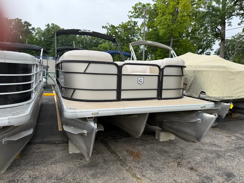 Slide: The Image of 2017 Sweetwater 22 pontoon boat parked on a lot with trees in the background. - 1