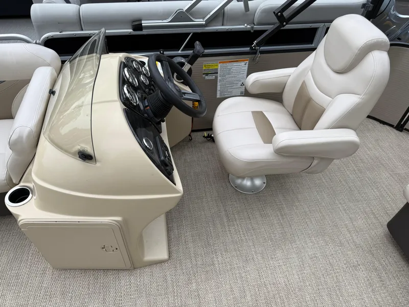 Slide: The Image of Captain's chair and helm of a 2017 Sweetwater 22 boat, featuring beige upholstery. - 12