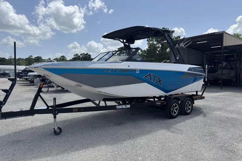 Slide: The Image of 2021 ATX Surf Boats 22 Type-S on trailer, blue and white design, parked outdoors. - 5