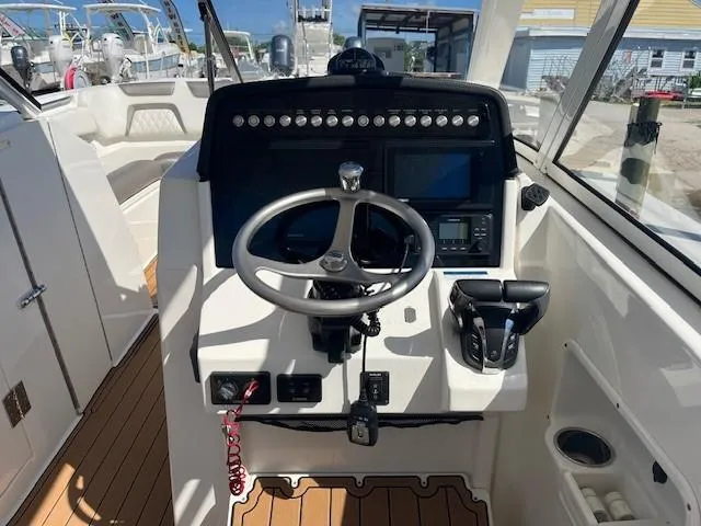 Slide: The Image of 2022 World Cat 296 DC boat helm with steering wheel, controls, and navigation screens. - 5