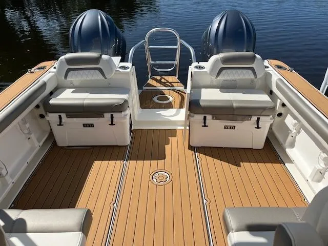 Slide: The Image of 2022 World Cat 296 DC boat deck with seating, coolers, and twin engines on calm water. - 7