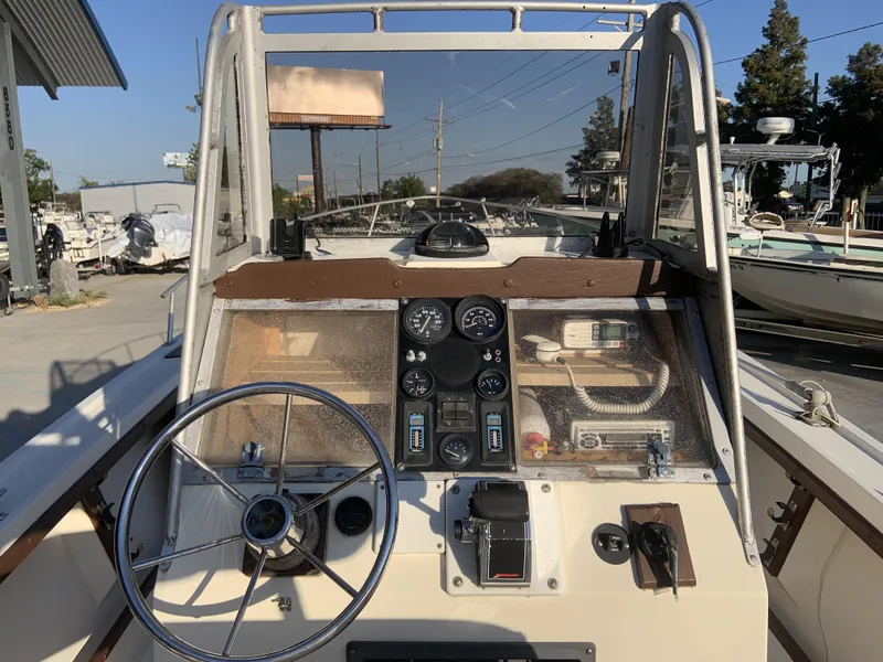 The Image of 1988 Mako 231 Center Console boat dashboard with steering wheel and gauges. - 2