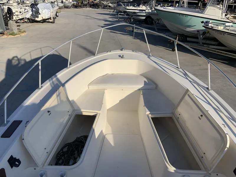 Slide: The Image of 1988 Mako 231 Center Console boat with open storage compartments, docked among other boats. - 6