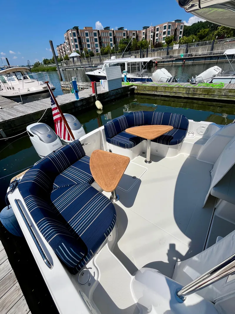 Slide: The Image of 2023 Back Cove 34O boat with striped seating and wooden tables at a marina. - 11