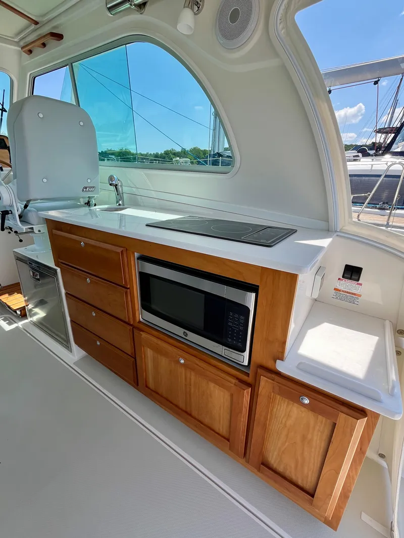 Slide: The Image of 2023 Back Cove 34O yacht interior with kitchenette, featuring wooden cabinets and modern appliances. - 15