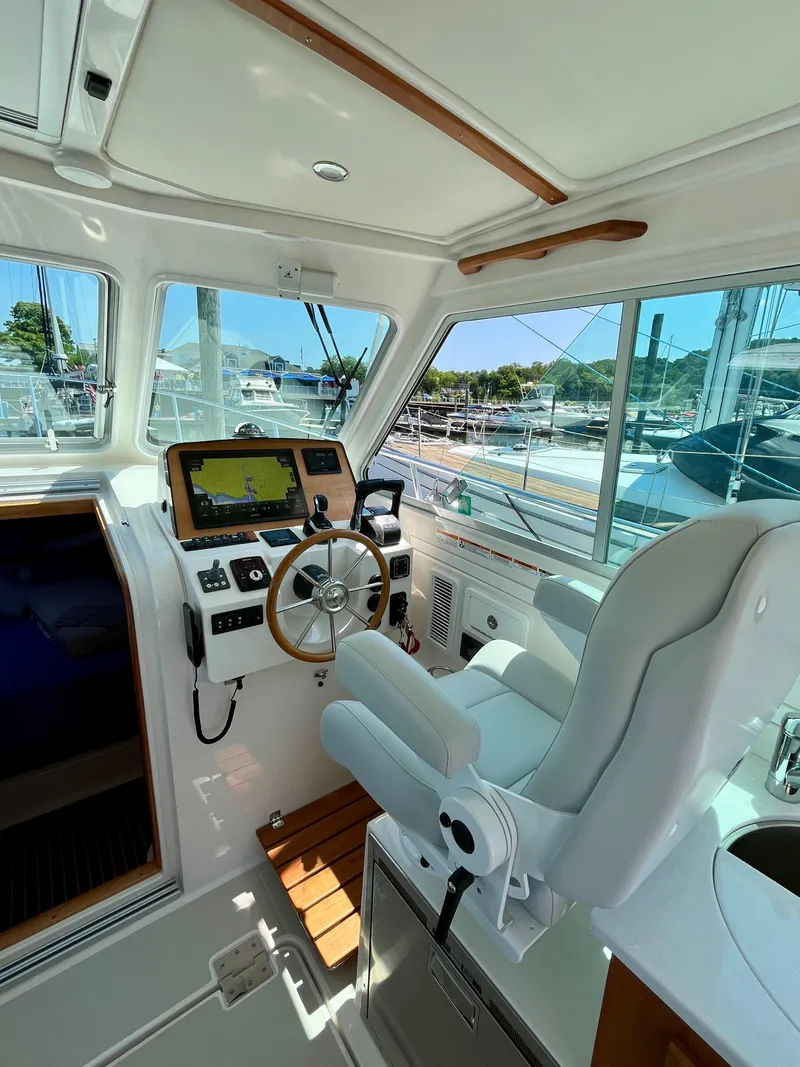 Slide: The Image of 2023 Back Cove 34O helm with modern controls and comfortable seating in a marina setting. - 18